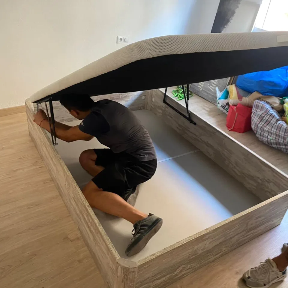 Trabajador montando una cama con base de almacenaje